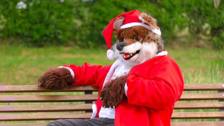 A whimsical moment with a furry costumed character donned in holiday attire, relaxing on a park bench.